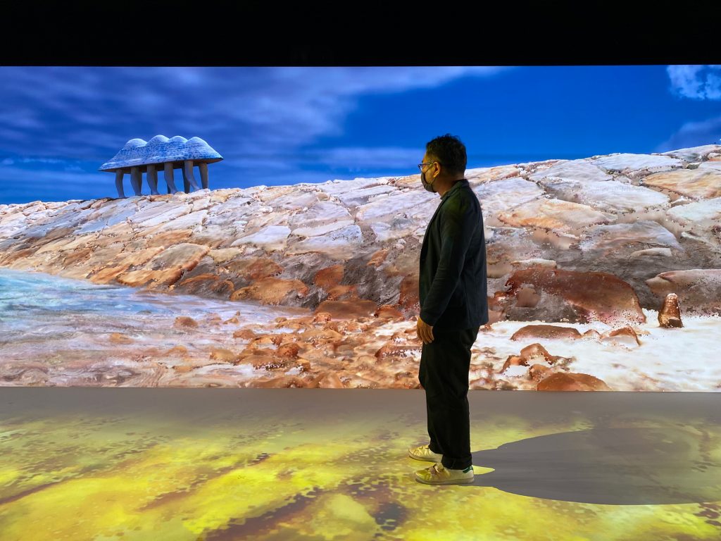 写真：男木島メタバースを背景に立つケノヒ代表の福井大和